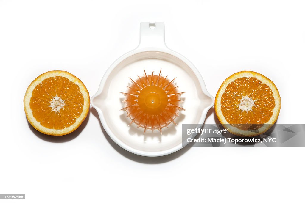 Juicer and orange cut in half on white background.