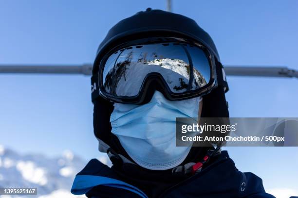 ski resort man on chairlift in helmet and medical mask - ski closeup stock-fotos und bilder