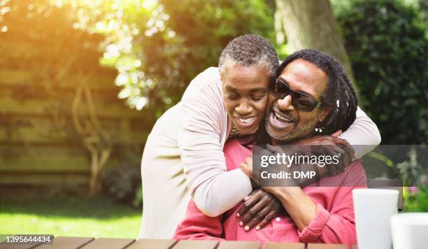 a happy and in love senior couple embracing in a garden. smiling mature man and woman hugging and sharing a romantic moment outdoors - blindness imagens e fotografias de stock