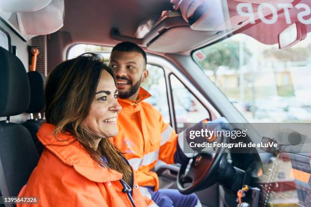 woman and young man paramedics smiling and happiness to coworker seen through ambulance windshield - paramedic photos et images de collection