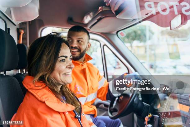 woman and young man paramedics smiling and happiness to coworker seen through ambulance windshield - pessoal de ambulância imagens e fotografias de stock