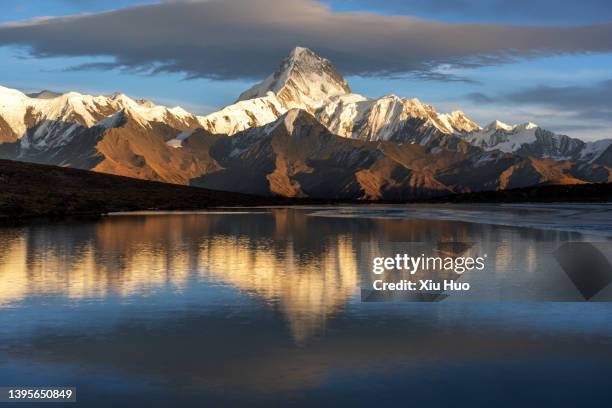 the snow-capped mountains by the lake under the sunset sky - mountain peak above clouds stock pictures, royalty-free photos & images