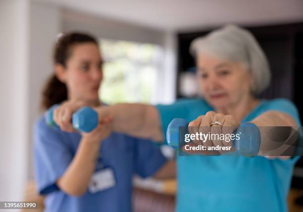 physical therapist helping a senior woman with her recovery at home - clean house stockfoto's en -beelden