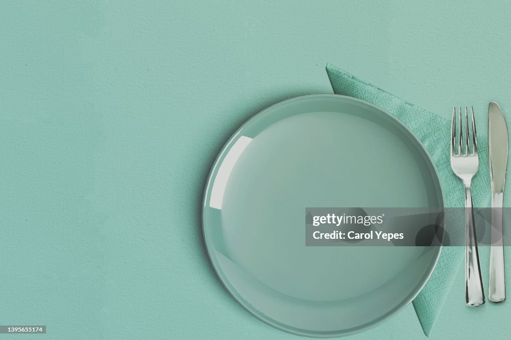 Empty plate table setting in mint green surface.top view