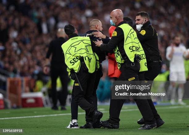 Stewards deal with a pitch invader that ran to Karim Benzema of Real Madrid bearing an Albania flag during the UEFA Champions League Semi Final Leg...