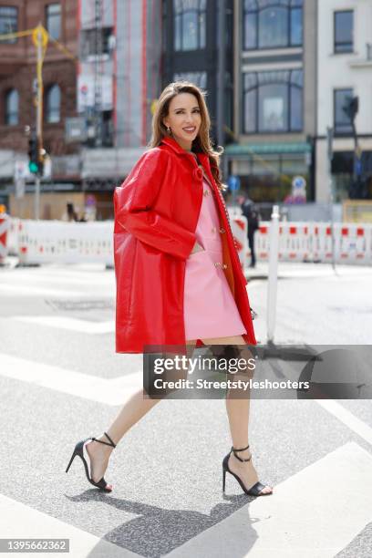 Influencer Alexandra Lapp wearing a red shiny cocoon coat by Louis Vuitton, a pink sleeveless mini dress by Louis Vuitton, black high heel sandals by...