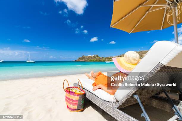 beautiful woman relaxing on sun lounger on idyllic beach - couché de soleil photos et images de collection