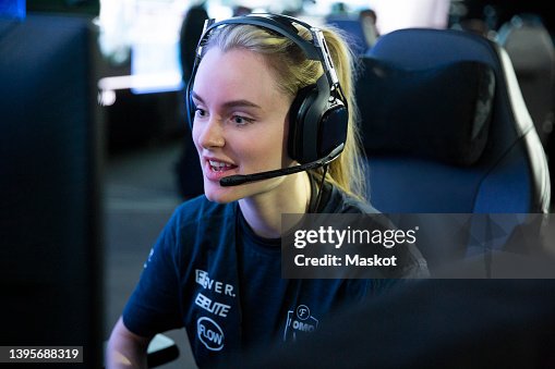Young female gamer wearing headphones while playing online video game at eSports tournament Young female gamer wearing headphones while playing online video game at eSports tournament