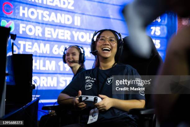 female gamer with controller laughing during esports tournament - esports foto e immagini stock