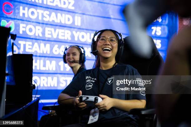 female gamer with controller laughing during esports tournament - massively multiplayer online game stock pictures, royalty-free photos & images