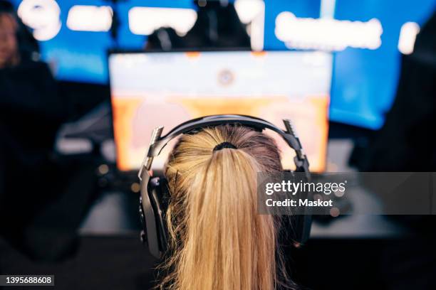 female gamer with blond ponytail playing online video game on computer during esports competition - esports stock pictures, royalty-free photos & images