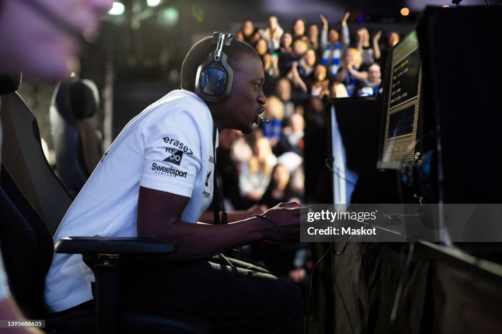 Concentrated male gamer with headphones playing online video game at eSports arena