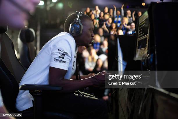 concentrated male gamer with headphones playing online video game at esports arena - esports stock pictures, royalty-free photos & images