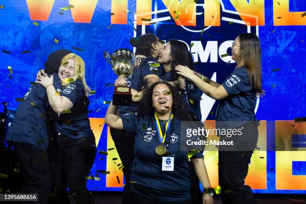 team of female gamers celebrating win while holding trophy of esports championship at arena - lgbt awards stockfoto's en -beelden