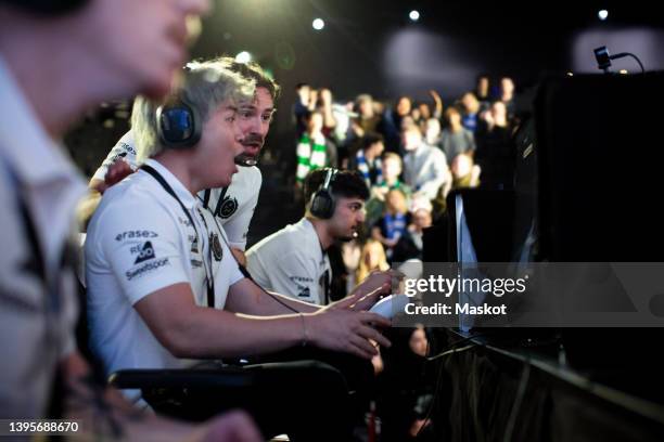 shocked male gamer playing online video game by coach at esports arena - esports foto e immagini stock