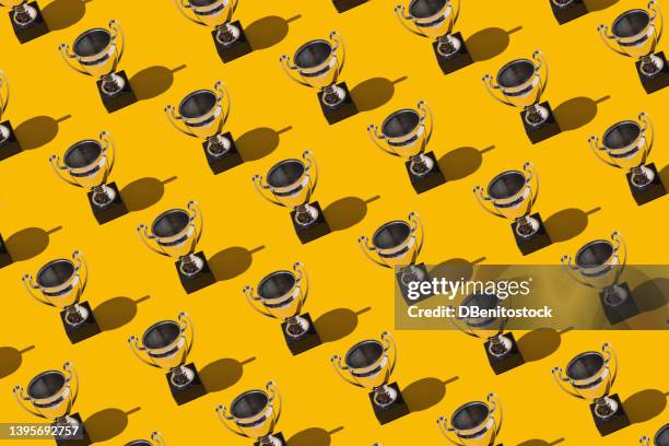 trophy cups winner champion cups pattern with hard shadow on yellow background. concept of victory, winner, european champion, world champion, soccer and sport. - the victory fotografías e imágenes de stock