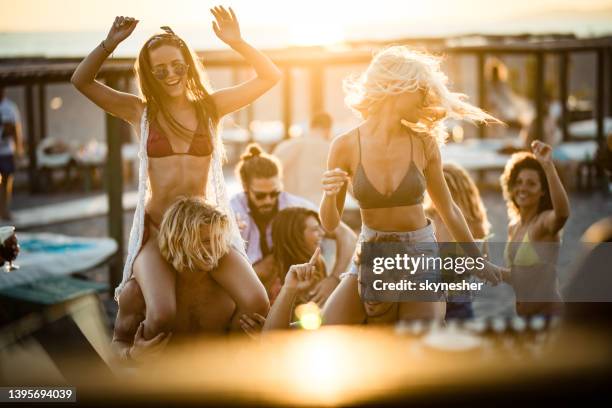 junge glückliche paare, die spaß auf eine beach-party bei sonnenuntergang. - beachparty stock-fotos und bilder