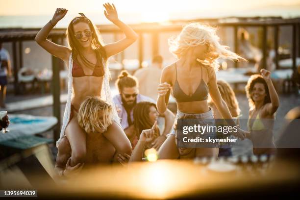 young happy couples having fun on a beach party at sunset. - beach party stock pictures, royalty-free photos & images