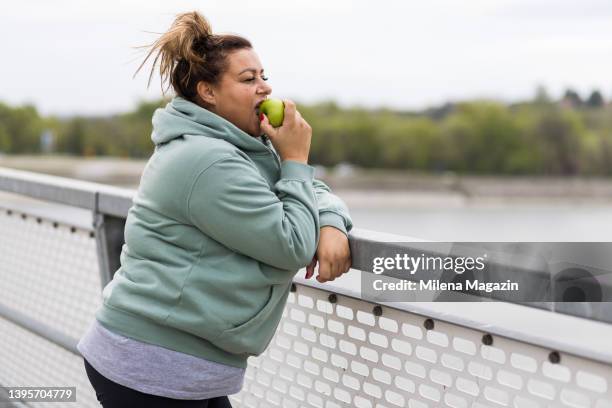 donna grassa di mezza età che mangia una mela dopo l'allenamento - grasso nutrienti foto e immagini stock