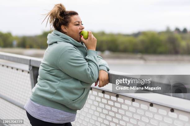 fat middle aged woman eating an apple after workout - fat nutrient 個照片及圖片檔