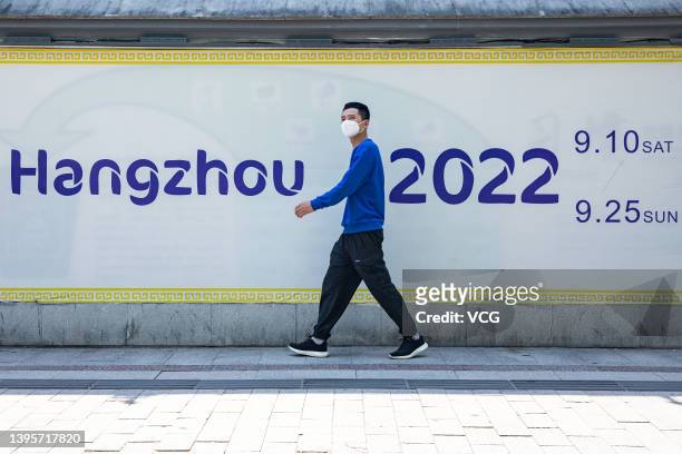 Pedestrian walks by an advertisement for the 19th Asian Games Hangzhou 2022 on May 6, 2022 in Hangzhou, Zhejiang Province of China.