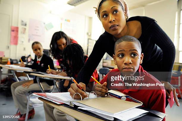 Teacher, Melanie Holmes, top right, instructs Erik Forrest, bottom right, on an assignment as Aquilah Pearson, far left, does her work while...
