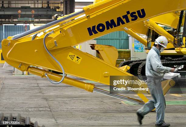 An employee walks past a Komatsu Ltd. Excavator on the production line of the company's plant in Hirakata City, Osaka, Japan, on Thursday, Feb. 23,...