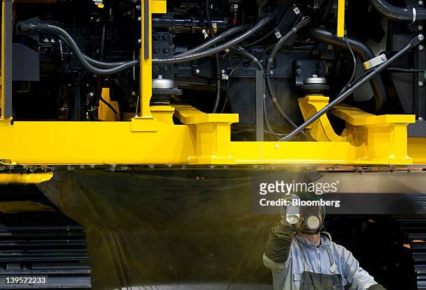 An employee sprays a Komatsu Ltd. Excavator on the production line of the company's plant in Hirakata City, Osaka, Japan, on Thursday, Feb. 23, 2012....