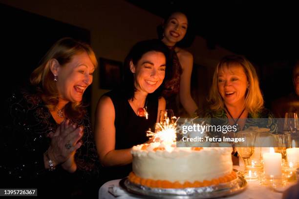 group of friends celebrating birthday in restaurant - older woman birthday stock pictures, royalty-free photos & images