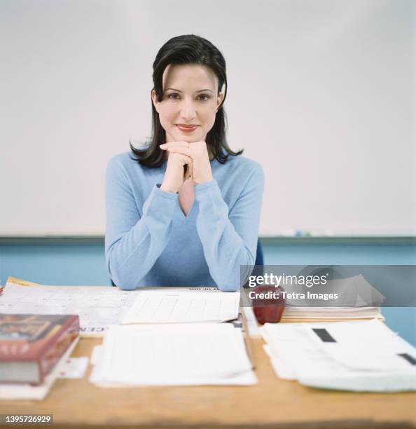 portrait of teacher sitting behind desk - tetra images teacher stock pictures, royalty-free photos & images