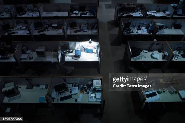 illuminated desk in dark office - oficina de plan abierto fotografías e imágenes de stock