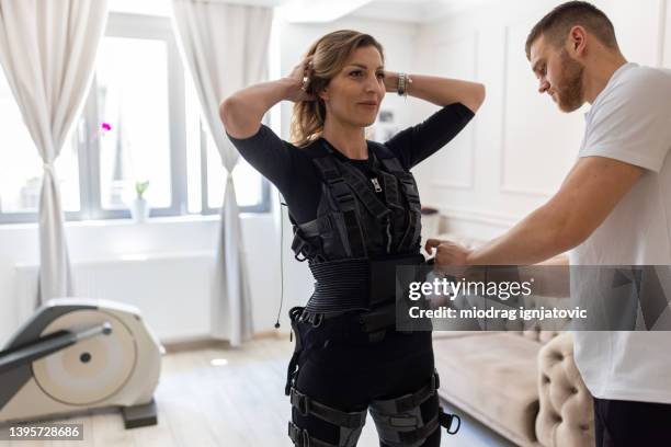 fitness instructor, preparing and adjusting the esm suit on a female client - electrode stock pictures, royalty-free photos & images