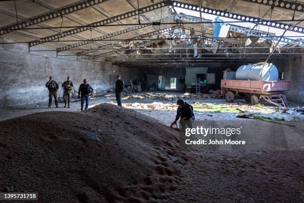 Local government officials and Ukrainian soldiers inspect a wheat grain warehouse earlier shelled by Russian forces on May 06, 2022 near the...