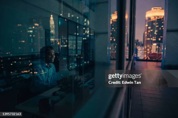 videochiamata del colletto bianco maschio indiano asiatico che lavora fino a tardi in ufficio da solo in condizioni di scarsa illuminazione - resilienza foto e immagini stock