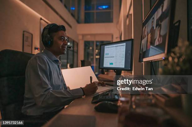 asian indian male white collar worker video call working late in office alone in low light - multiple screens stock pictures, royalty-free photos & images