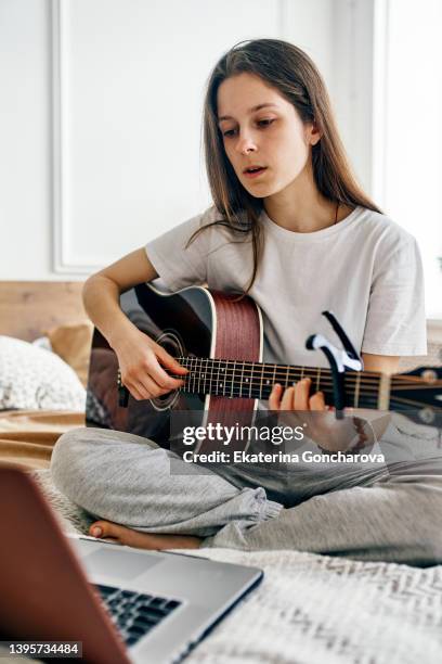 a young beautiful woman plays the guitar at home. - akustikgitarre stock-fotos und bilder