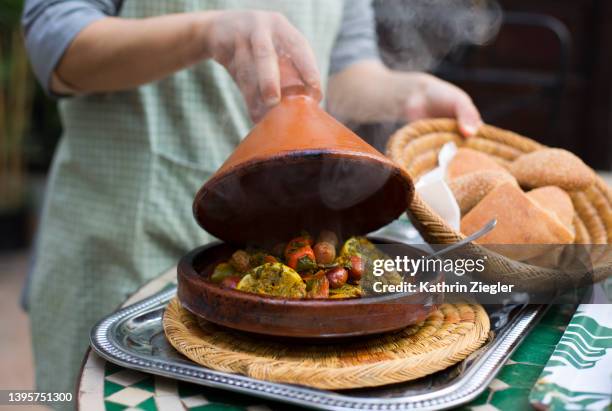 woman lifting lid of tajine - nordafrika stock-fotos und bilder