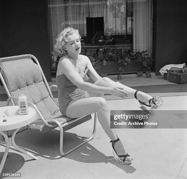 American actress Marilyn Monroe applies Nivea lotion to her legs, circa 1951.