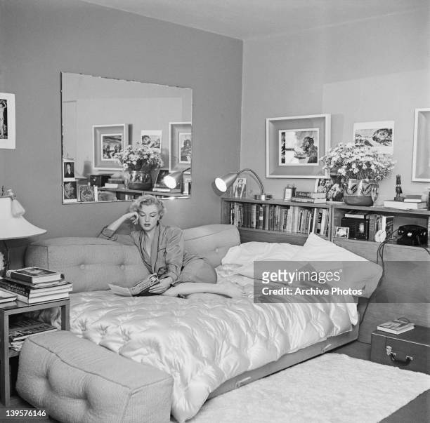 American actress Marilyn Monroe relaxes on a sofa bed, circa 1951. The book she is reading is 'The Poetry and Prose of Heinrich Heine'.