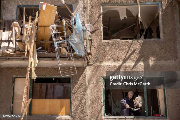 Man throws debris from the window of a residential apartment block damaged one day before by a Russian missile strike on May 06, 2022 in Kramatorsk,...