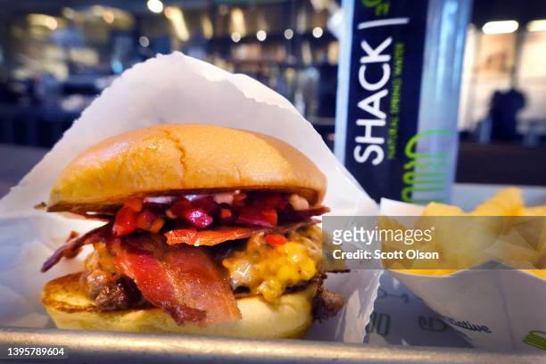 In this photo illustration a bacon cheeseburger sandwich and fries are served at a Shake Shack restaurant on May 06, 2022 in Chicago, Illinois....