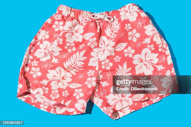 pink men's trunks with leaves and white flowers with hard shadow on light blue background. concept of heat, summer and sunlight. - floral pattern water colour stock-fotos und bilder