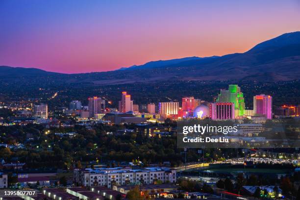 reno skyline in der abenddämmerung mit illuminationen und einem bunten himmel - nevada stock-fotos und bilder