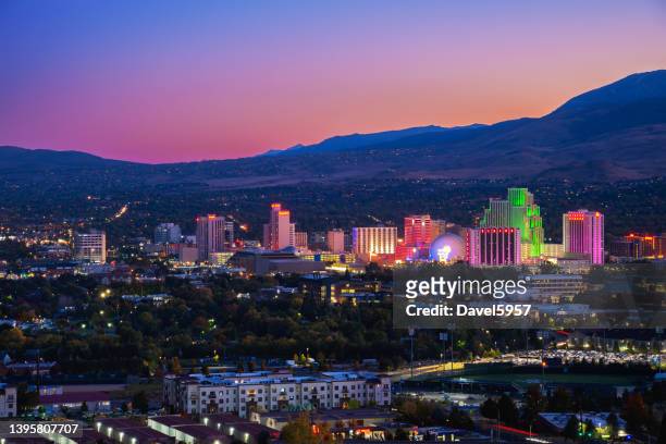 reno skyline at dusk with illuminations and a multicolored sky - nevada stock pictures, royalty-free photos & images