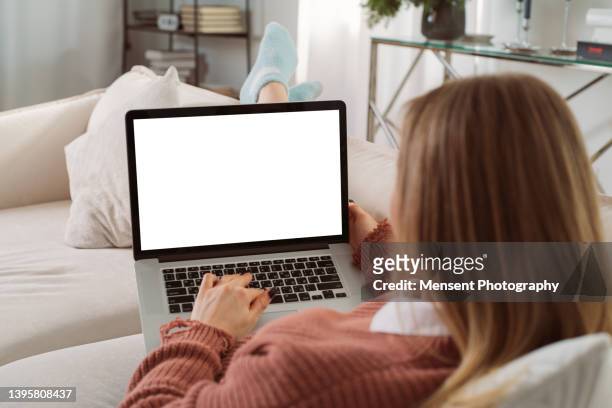 casual young woman lying on couch at home using laptop in white screen, close-up - homepage stock pictures, royalty-free photos & images