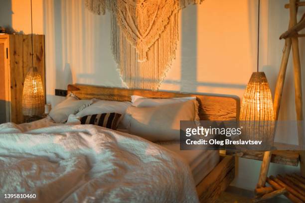 evening romantic mood in bedroom. stylish room with handmade design elements in boho style. beautiful light in cozy home. - estilo boho fotografías e imágenes de stock