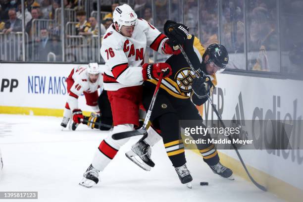 Brady Skjei of the Carolina Hurricanes and Brad Marchand of the Boston Bruins battle for control of the puck during the first period Game Three of...