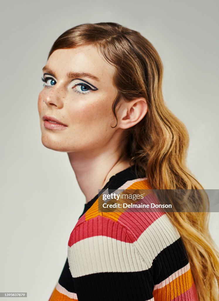 An attractive young woman dressed up in 60’s wear against a grey studio background. Portrait of a beautiful model looking at the camera dressed in a retro style