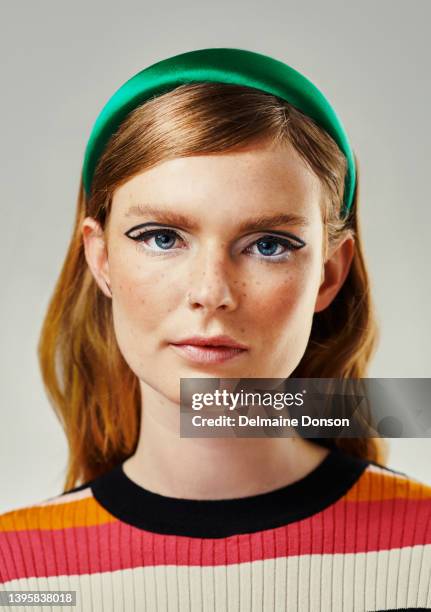 an attractive young woman dressed up in 60’s wear against a grey studio background. portrait of a beautiful model looking at the camera dressed in a retro style - portrait retro woman stock pictures, royalty-free photos & images