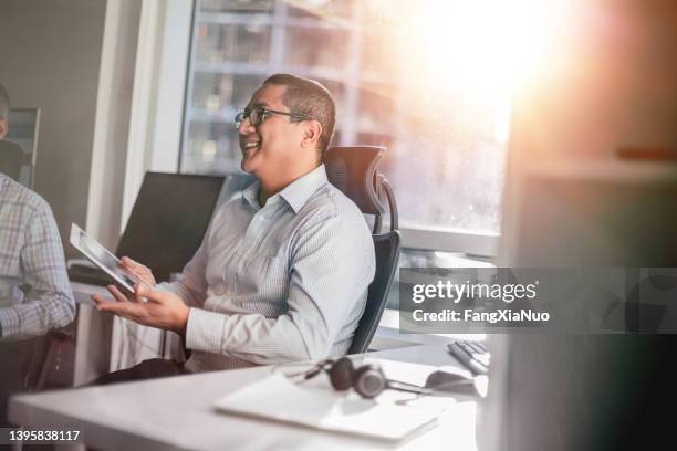 hispanic businessman talking with colleagues in modern office meeting - sunny office stock pictures, royalty-free photos & images